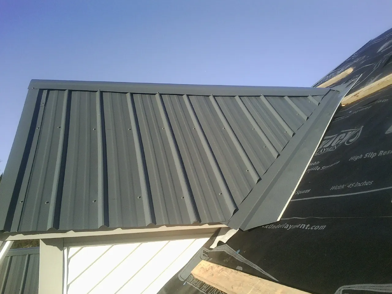Gray metal roof panels going on over a garage gable in Bear Creek